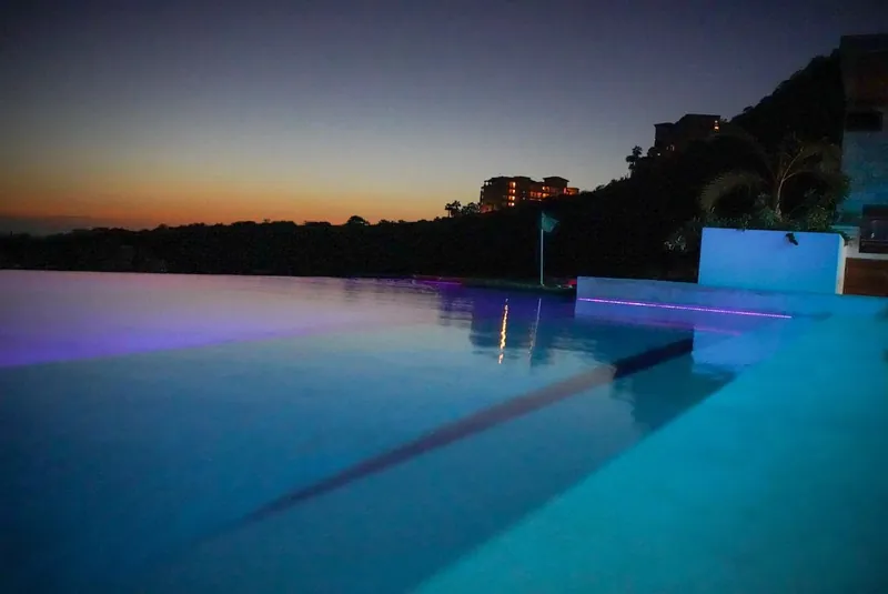 Casa Texas infinity pool glowing purple and blue at dusk