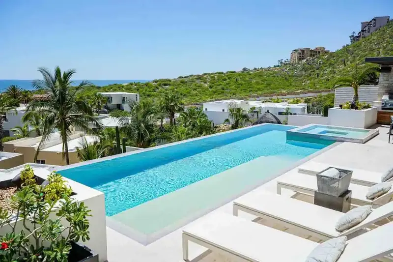 Casa Texas daytime infinity pool and white lounge chairs with ocean view